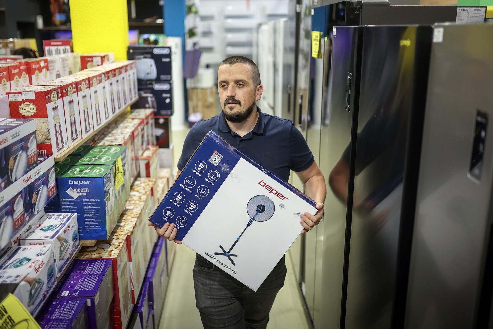 Tarik Fatic, one of the owners of "Only fools and horses ltd." home appliance store, brings a fan to a customer in Hadzici, suburb of Sarajevo, Bosnia, Wednesday, June 4, 2025. (AP Photo/Armin Durgut)