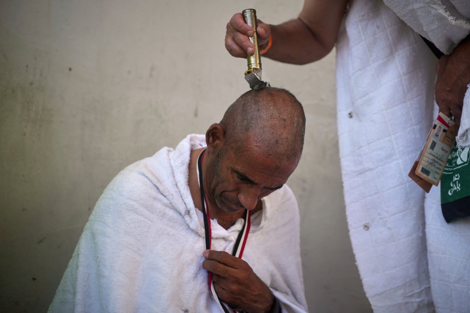 A Muslim pilgrim shaves his head, a significant part of the Umrah and Hajj rituals in Islam, during the symbolic stoning of the devil, the last rite of the annual Hajj, in Mina near the holy city of Mecca, Saudi Arabia, Friday, June 6, 2025. (AP Photo/Amr Nabil)
