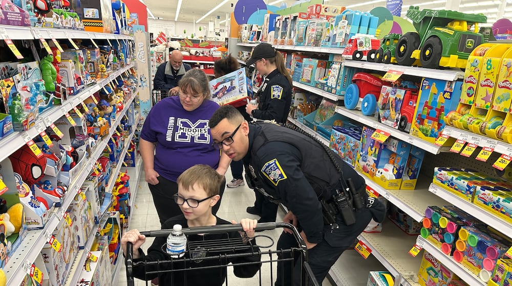 Middletown Division of Police officer Justin Beamis helps Luke Wilburn shop for presents during the Mike Davis Shop with a Cop program on Dec. 13 at the Middletown Meijer. Grandmother Rachel Cobb looks on. RICK MCCRABB/CONTRIBUTED