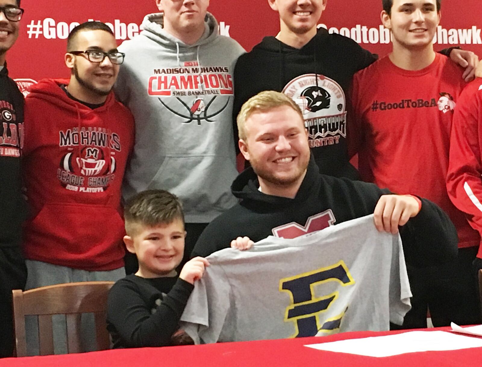 Madison’s Max Evans poses with his teammates and friends, including second-grader Matt Honhart, during Friday afternoon’s signing ceremony in the high school media center. Evans signed with East Tennessee State University to continue his football career. RICK CASSANO/STAFF