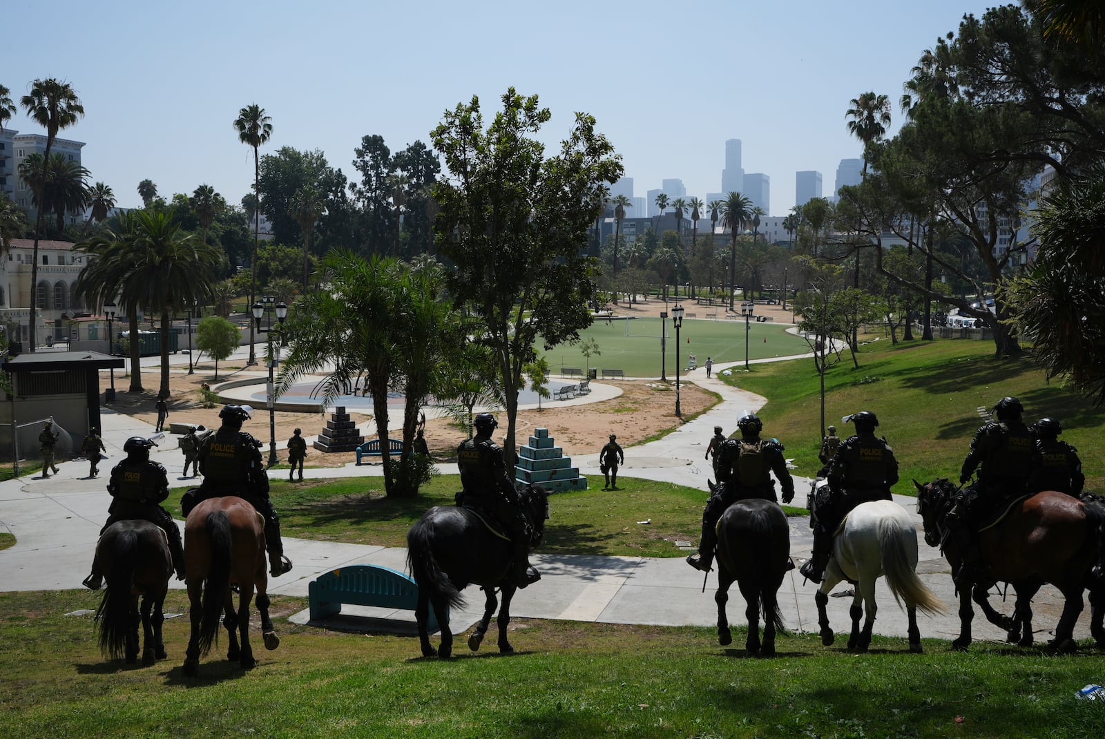 Federal agents ride on horseback at MacArthur Park Monday, July 7, 2025, in Los Angeles. (AP Photo/Damian Dovarganes)