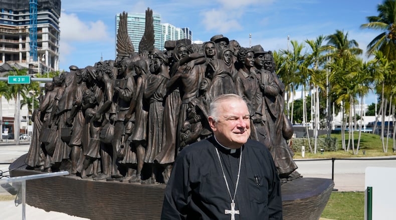 FILE - Archbishop of Miami Thomas Wenski poses in front of a traveling bronze sculpture titled "Angels Unawares," before blessing it, Feb. 10, 2021, in downtown Miami. (AP Photo/Wilfredo Lee, File)