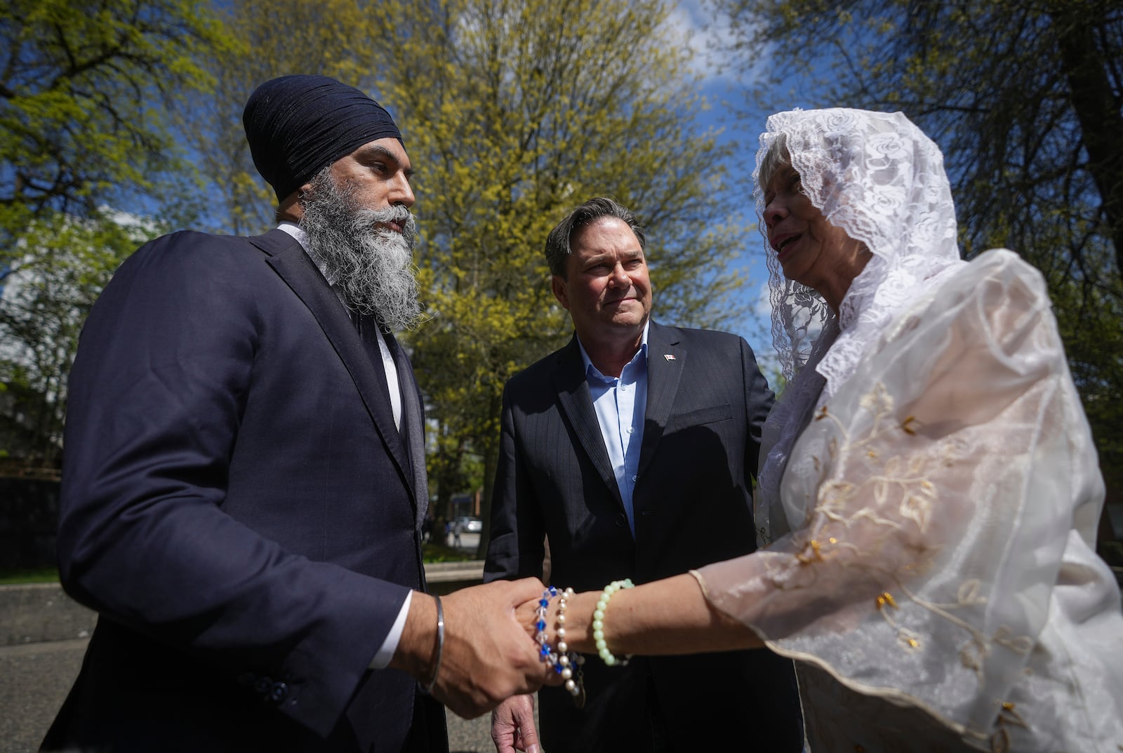 NDP Leader Jagmeet Singh talks with Rosita Taruc, right, as NDP candidate for Vancouver Kingsway Don Davies, back centre, listens as they arrive to attend mass at St. Mary's Parish after multiple people that were stuck by a car were killed at a Filipino heritage festival, in Vancouver, British Columbia, Sunday, April 27, 2025. (Darryl Dyck/The Canadian Press via AP)