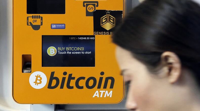 In this Dec. 21, 2017, file photo, a woman walks past the Bitcoin ATM in Hong Kong. (AP Photo/Kin Cheung)
