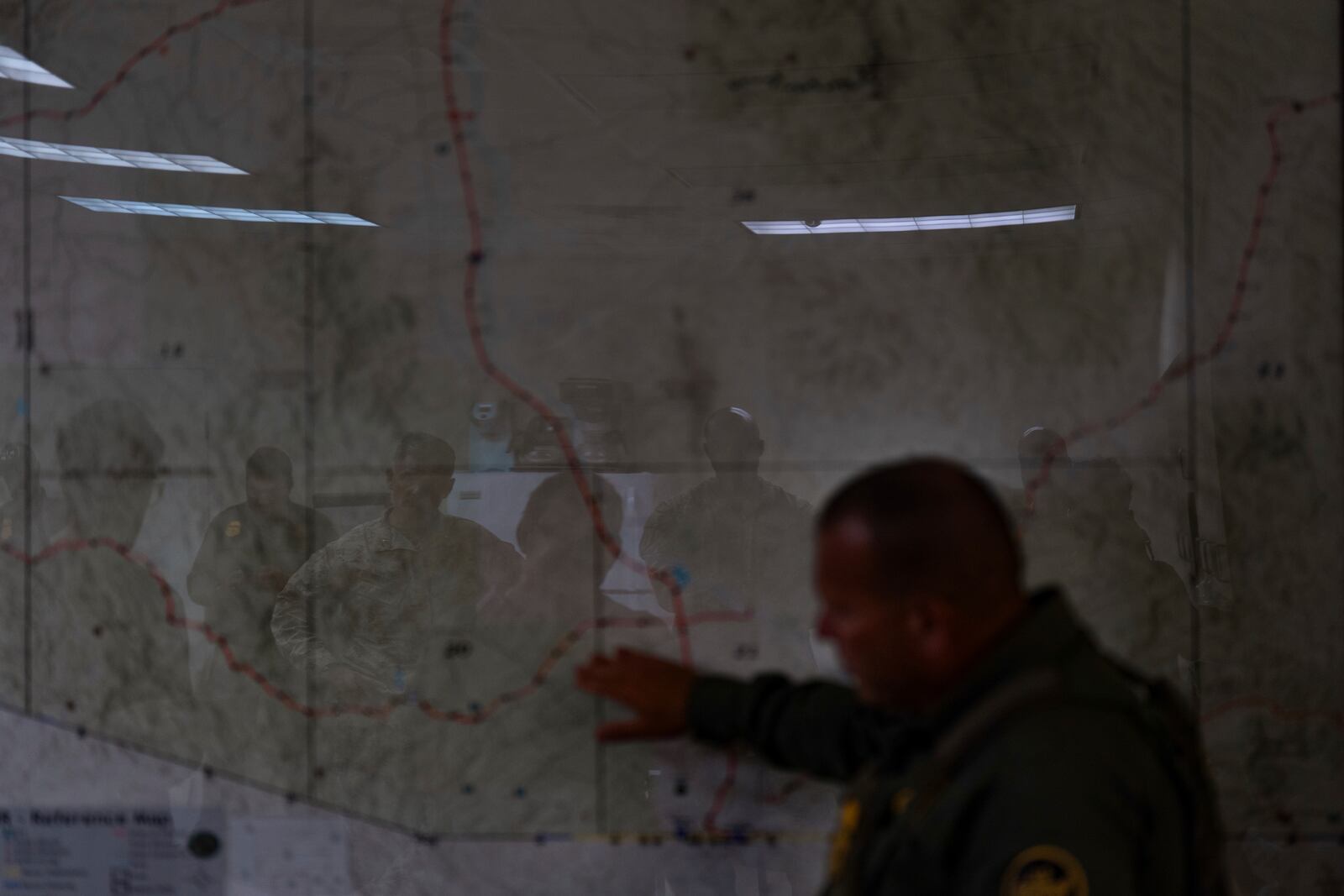 U.S. military personnel are reflected on a map as they listen to Jose Luis Maheda during a briefing at the U.S. Border Patrol station in Nogales, Ariz., Tuesday, July 22, 2025. (AP Photo/Jae C. Hong)