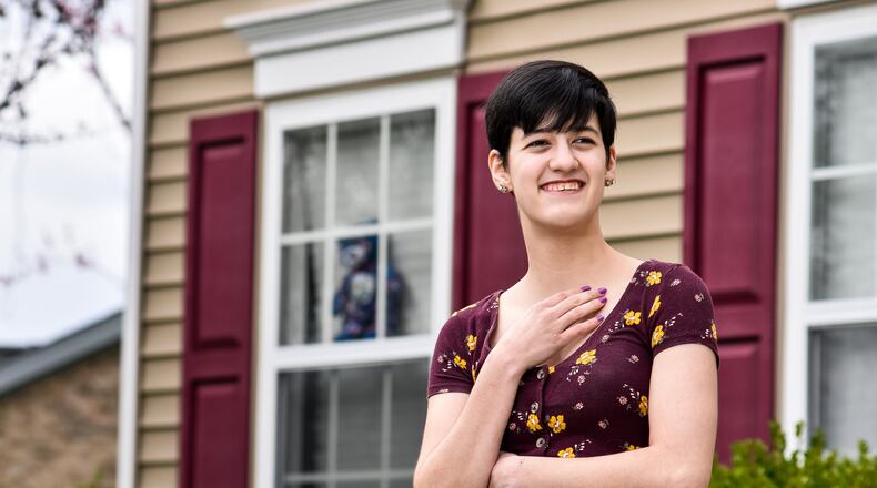Asia Werner stands outside her home in West Chester Township Wednesday, April 1, 2020. Werner is a student at University of Cincinnati’s College of Nursing but is now taking online classes at home due to the coronavirus (COVID-19) pandemic. She had a heart transplant when she was one and she has an immune disorder called CVID (Combined Immune Deficiency Syndrome) that makes her highly susceptible to infection. Asia would normally be staying in a dorm on the University of Cincinnati campus but the threat of coronavirus has forced her to stay at home to avoid contact with others. She has placed stuffed animals in the front windows to bring a smile to faces of those who may pass by. NICK GRAHAM / STAFF