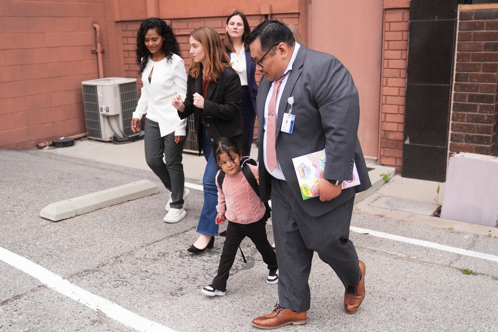 A 4-year-old Mexican girl, who has short bowel syndrome, holds the hand of Yonny Aguilar, a senior paralegal at Public Counsel, as she and her mother, far left, leave a news conference in Los Angeles, Wednesday, May 28, 2025, after their humanitarian parole was terminated and they were ordered to self-deport. (AP Photo/Jae C. Hong)