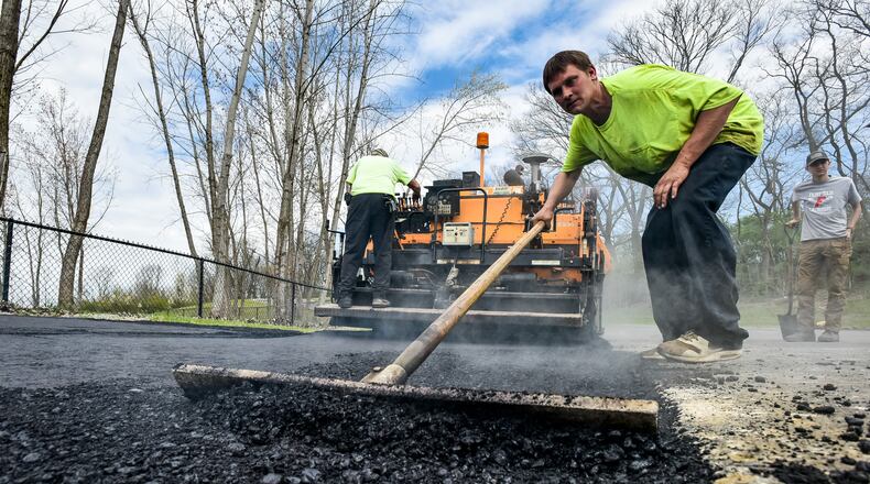 Chase Ditmyer with Barry L. Brown Paving spreads asphalt as they add parking spots at FurField Dog Park Friday, April 3, 2020 in Fairfield. The paving company is working during the coronavirus pandemic and is using the time the park is closed down to get needed parking spots added. NICK GRAHAM / STAFF