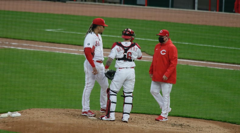 Reds starter Luis Castillo, catcher Tucker Barnhart and pitching coach Derek Johnson meet on the mound during a game against the Diamondbacks on Tuesday, April 20, 2021, at Great American Ball Park in Cincinnati. David Jablonski/Staff