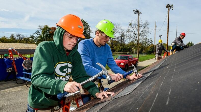 Ryan Kemp, left, and Nicholas Caudill, right, seniors in the Butler Tech construction technologies program, puts shingles on the roof at the baseball dugouts at Crawford Woods Park along Hancock Avenue in Hamilton. NICK GRAHAM/STAFF