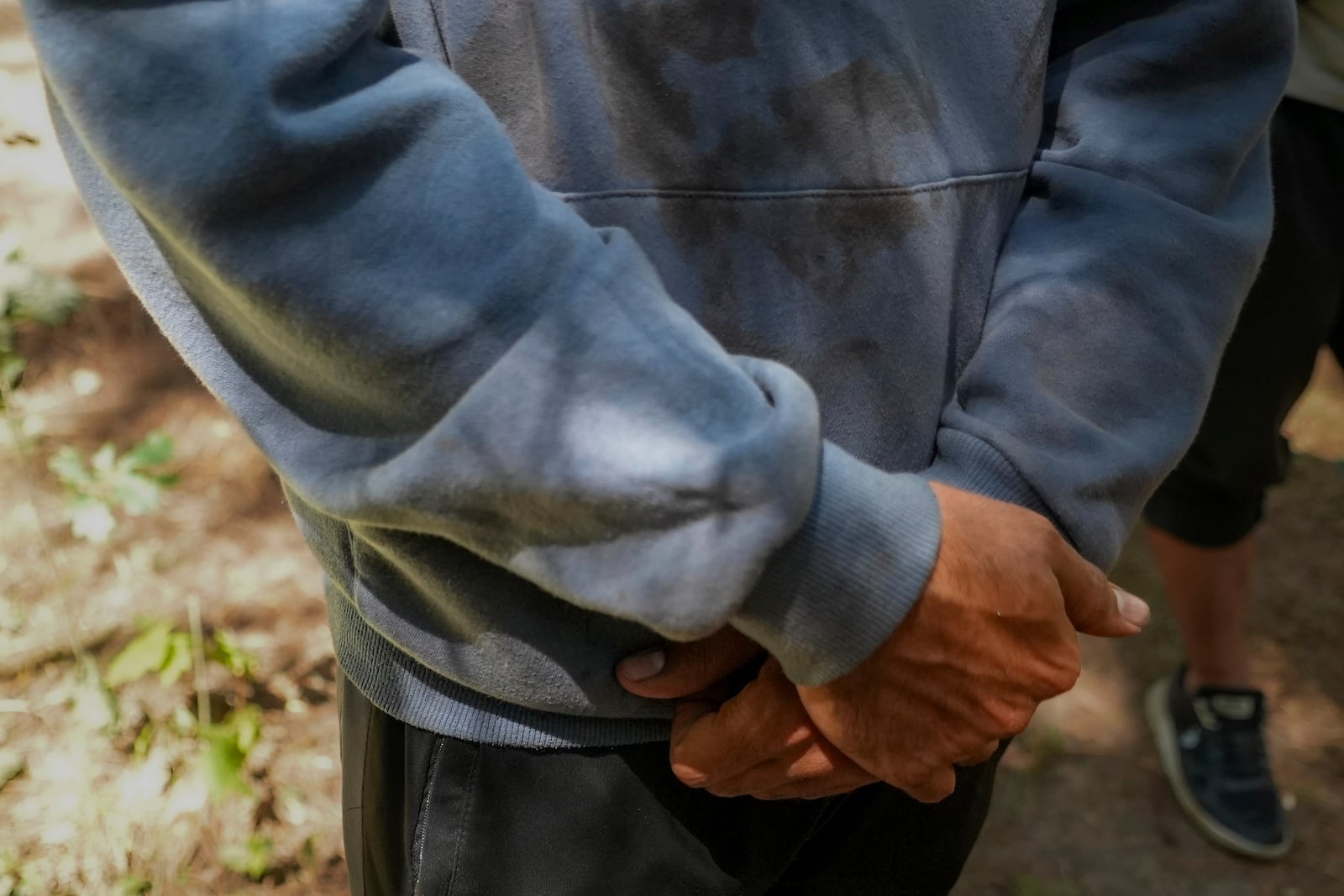 Qassim, 26, a Palestinian, wears a hoodie stained with what he said is his wife Anouar's blood, in the Ecault forest northern France, Thursday, July 3, 2025. (AP Photo/Nicolas Garriga)