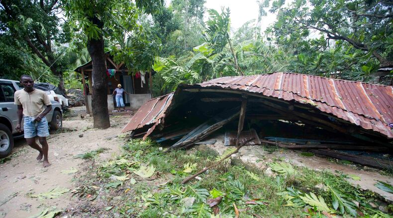 A man stands next to a home flatten by Hurricane Matthew, in Grand Goave, Haiti, Wednesday, Oct. 5, 2016. Rescue workers in Haiti struggled to reach cutoff towns and learn the full extent of the death and destruction caused by Hurricane Matthew as the storm began battering the Bahamas on Wednesday and triggered large-scale evacuations along the U.S. East Coast. ( AP Photo/Dieu Nalio Chery)