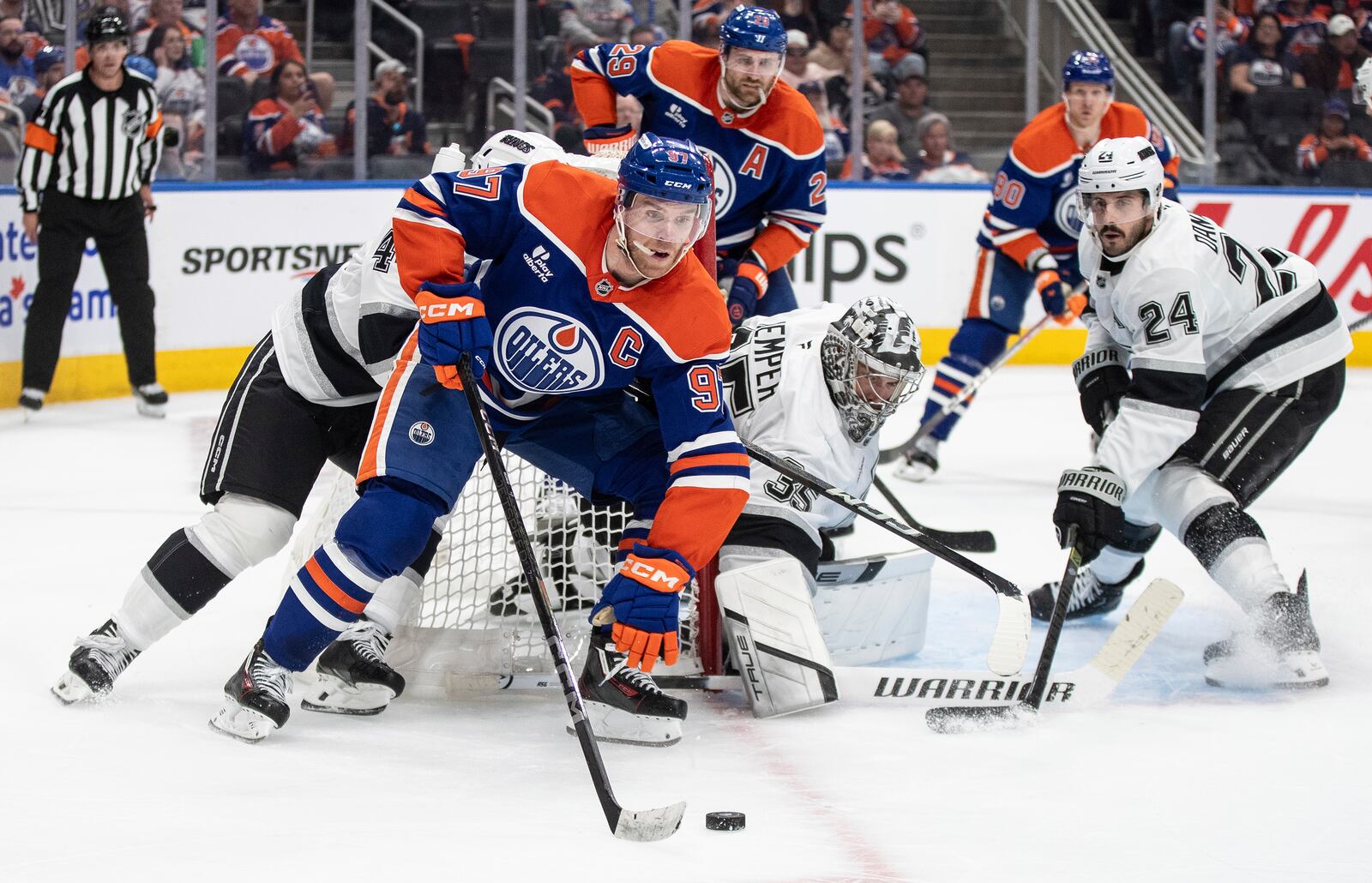 Los Angeles Kings' goalie Darcy Kuemper (35) looks for the puck as Edmonton Oilers' Connor McDavid (97) skates around the net and Kings' Phillip Danault (24) defends during the second period of an NHL hockey playoff game in Edmonton, Alberta, Friday, April 25, 2025. (Jason Franson/The Canadian Press via AP)