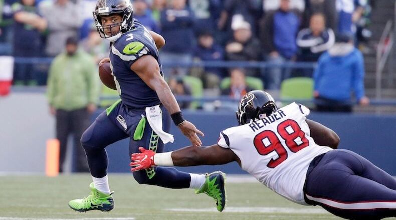 Seattle Seahawks quarterback Russell Wilson, left, scrambles away from Houston Texans' D.J. Reader in the second half of an NFL football game, Sunday, Oct. 29, 2017, in Seattle. The Seahawks won 41-38. (AP Photo/Elaine Thompson)