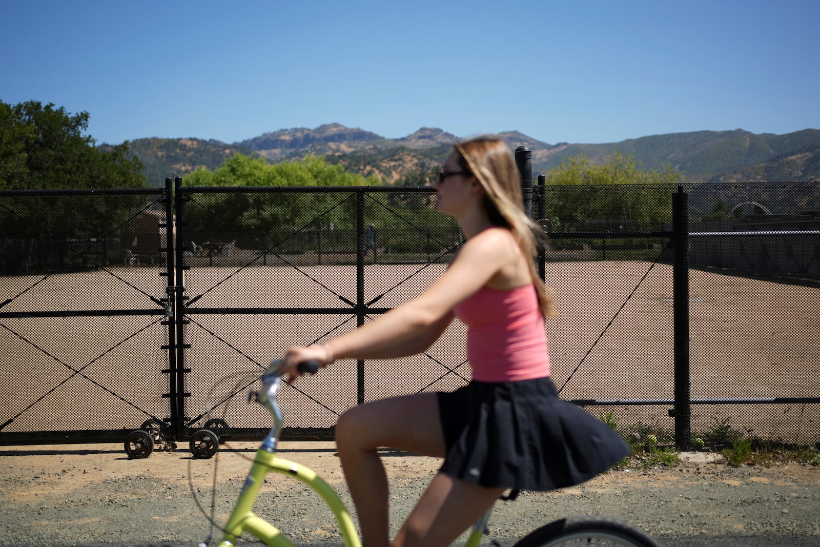 Kendell Weis pedals on a popular bike path past a dog park that used to house noisy diesel generators on Tuesday, May 27, 2025, in Calistoga, Calif. (AP Photo/Annika Hammerschlag)