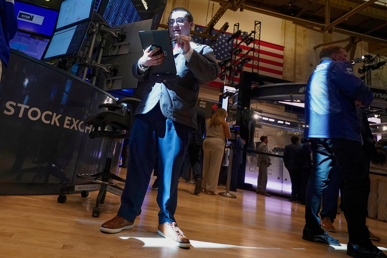Trader Drew Cohen is lit by a ray of sunshine on the floor of the New York Stock Exchange, Tuesday, May 20, 2025. (AP Photo/Richard Drew)