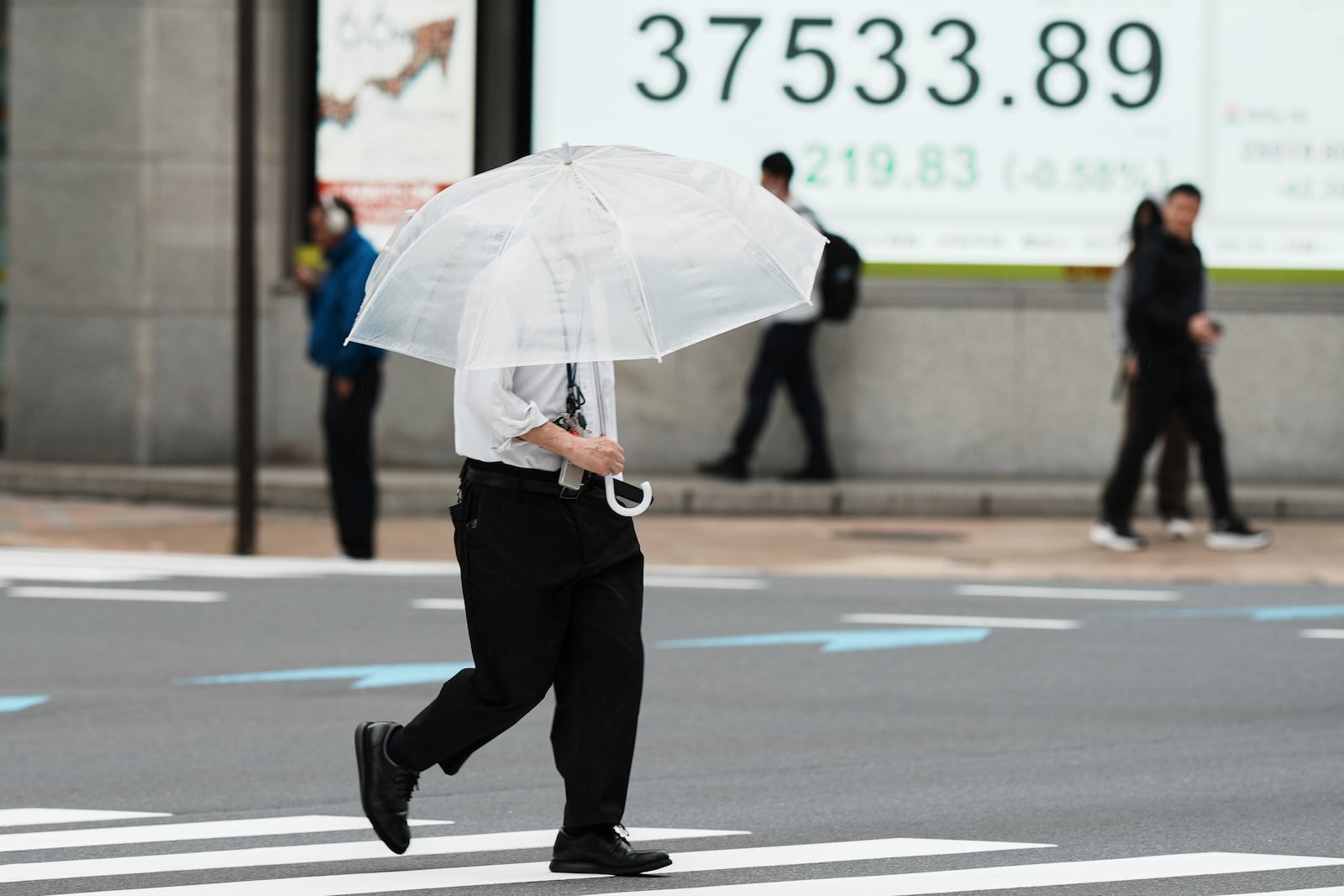 A person walks near an electronic stock board showing Japan's Nikkei index at a securities firm Monday, May 19, 2025, in Tokyo. (AP Photo/Eugene Hoshiko)