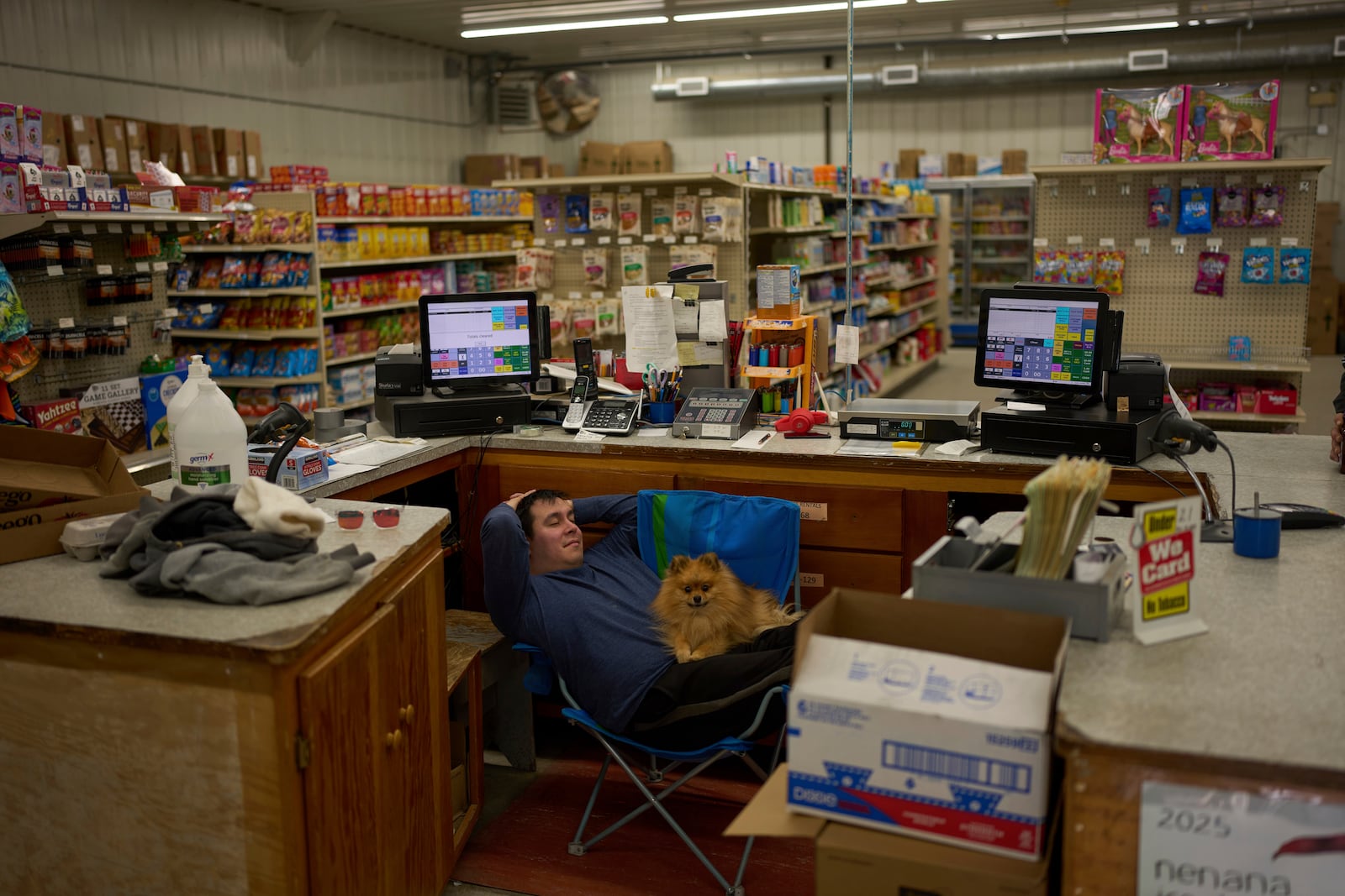 Brenden Sweetsir waits with dog Rex for customers at Sweetsirs store Wednesday, May 21, 2025, in Galena, Alaska. (AP Photo/John Locher)