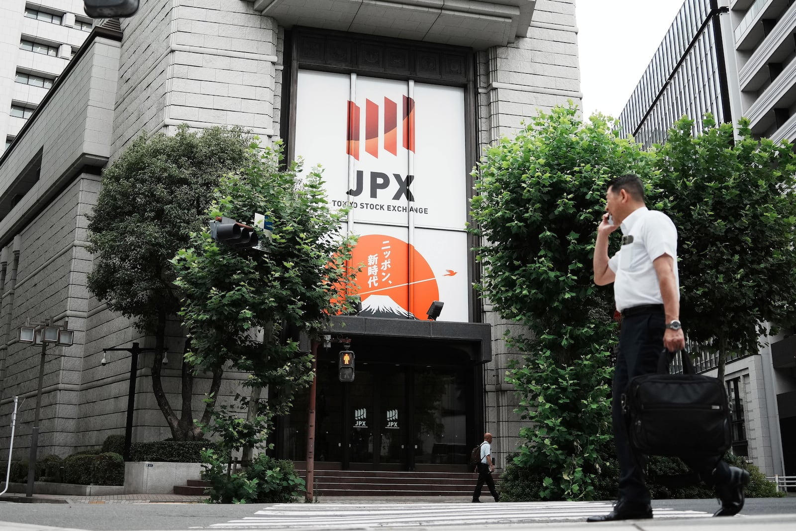 A person walks in front of Tokyo Stock Exchange building Friday, July 11, 2025, in Tokyo. (AP Photo/Eugene Hoshiko)