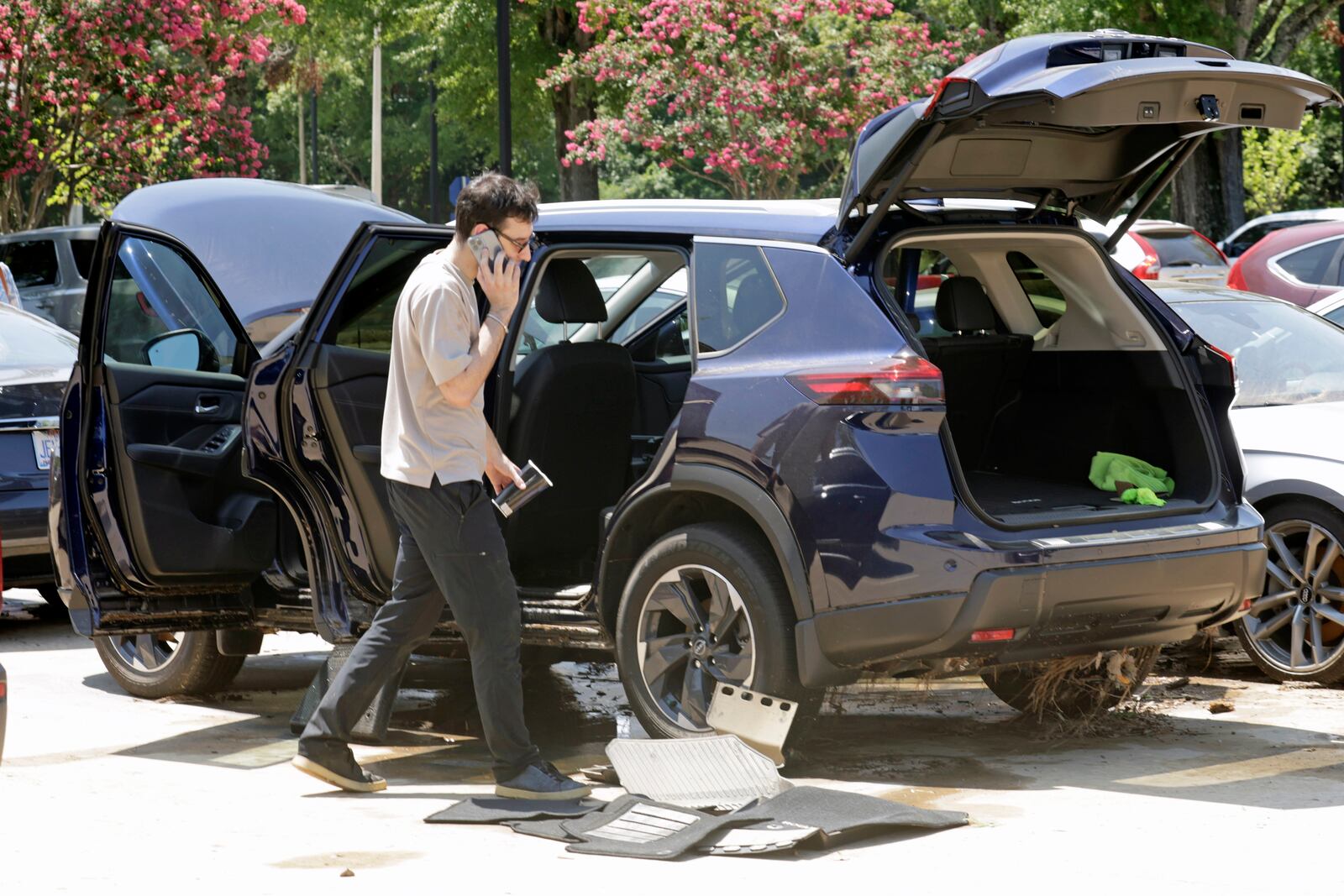 A man tries to dry his car out in a parking lot at University Place shopping center after it was flooded out during tropical storm Chantal, Monday, July 7, 2025, in Chapel Hill, N.C. (AP Photo/Chris Seward)
