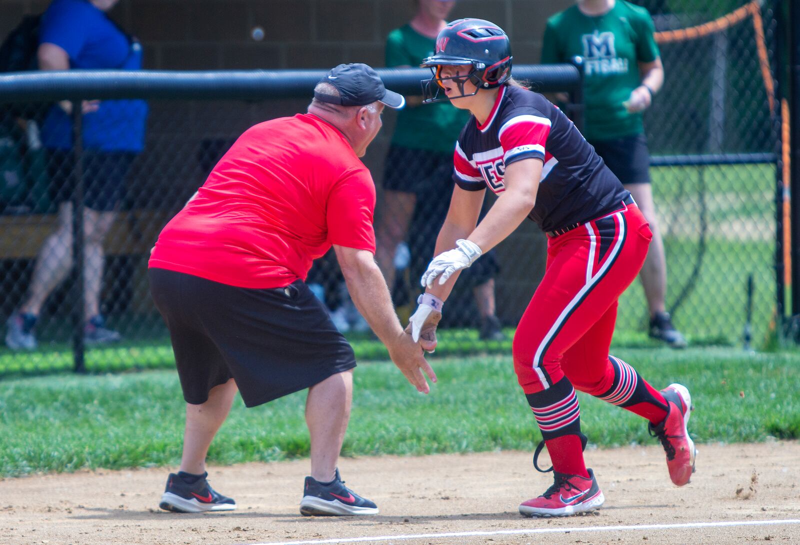 Lakota West's KK Mathis celebrates her first-inning home run with Firebirds coach Keith Castner during Thursday's Division I regional semifinal vs. Mason at Centerville High School. Jeff Gilbert/CONTRIBUTED