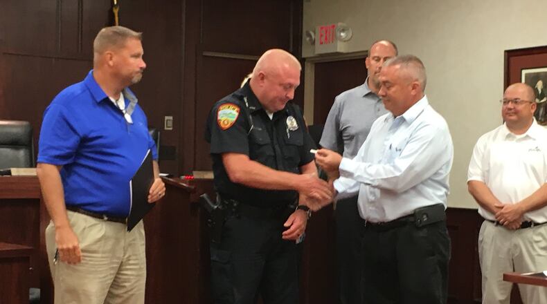 Franklin police Officer Dennis Shannon was recently presented a Meritorious Service Award for the saving the life of a three-year-old girl who was choking on a hot dog in March. At right is Mayor Todd Hall, Shannon, police Chief Russell Whitman, left. ED RICHTER/STAFF