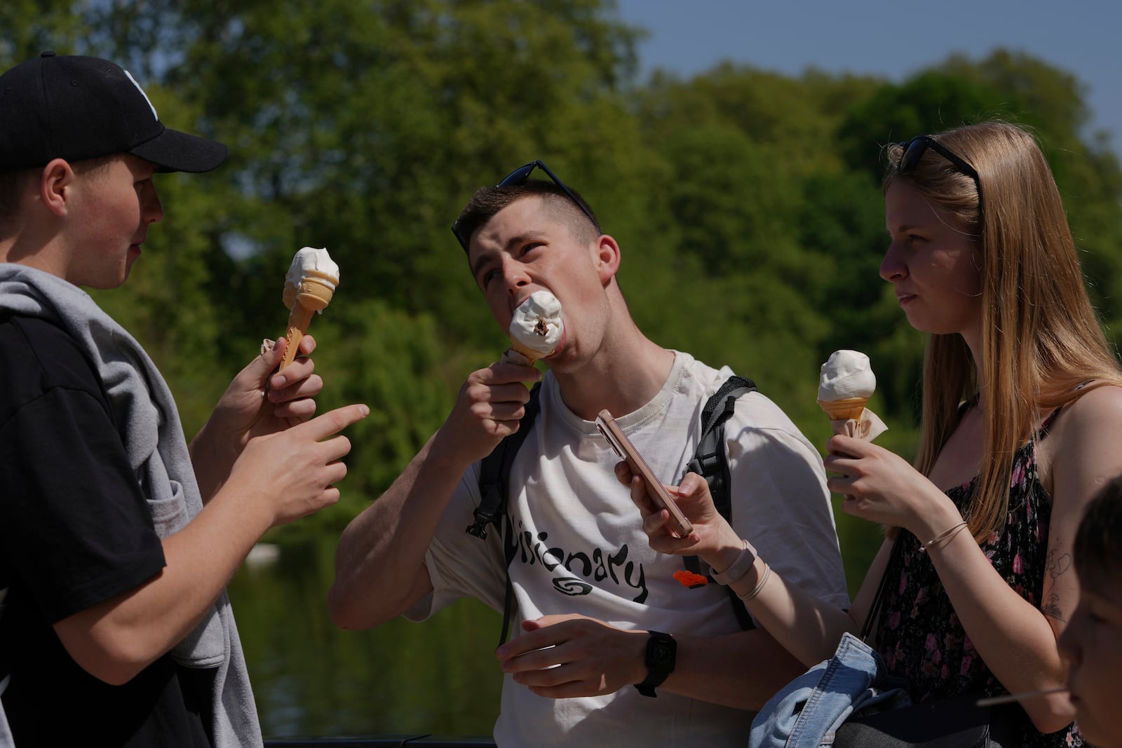 People have ice-cream on a sunny day at a park in London, Wednesday, April 30, 2025. (AP Photo/Kin Cheung)