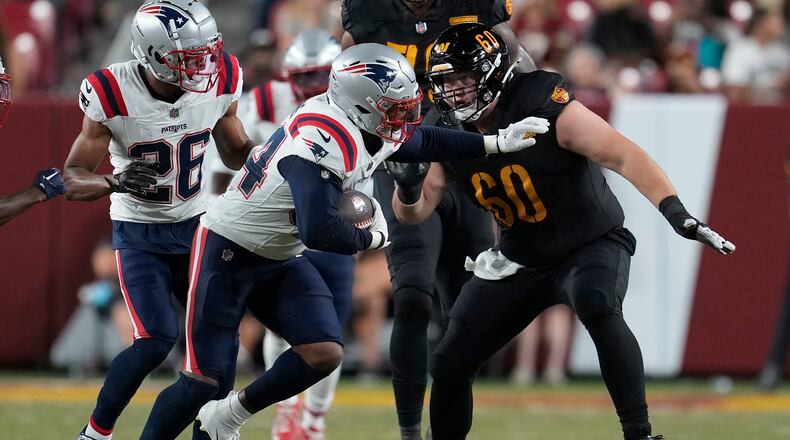 New England Patriots linebacker Joe Giles-Harris, middle left, returns an interception against Washington Commanders guard Michael Deiter (60) during the first half of a preseason NFL football game, Sunday, Aug. 25, 2024, in Landover, Md. (AP Photo/George Walker IV)