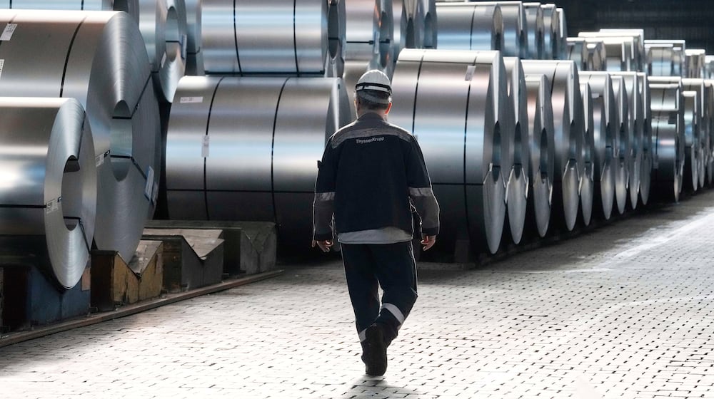 FILE - A steel worker walks beside steel coils during a visit of EU Commissioner for Prosperity and Industrial Strategy Stephane Sejourne at the Thyssenkrupp steelworks in Duisburg, Germany, after the EU Steel Action plan was presented, Thursday, March 20, 2025. (AP Photo/Martin Meissner, File)