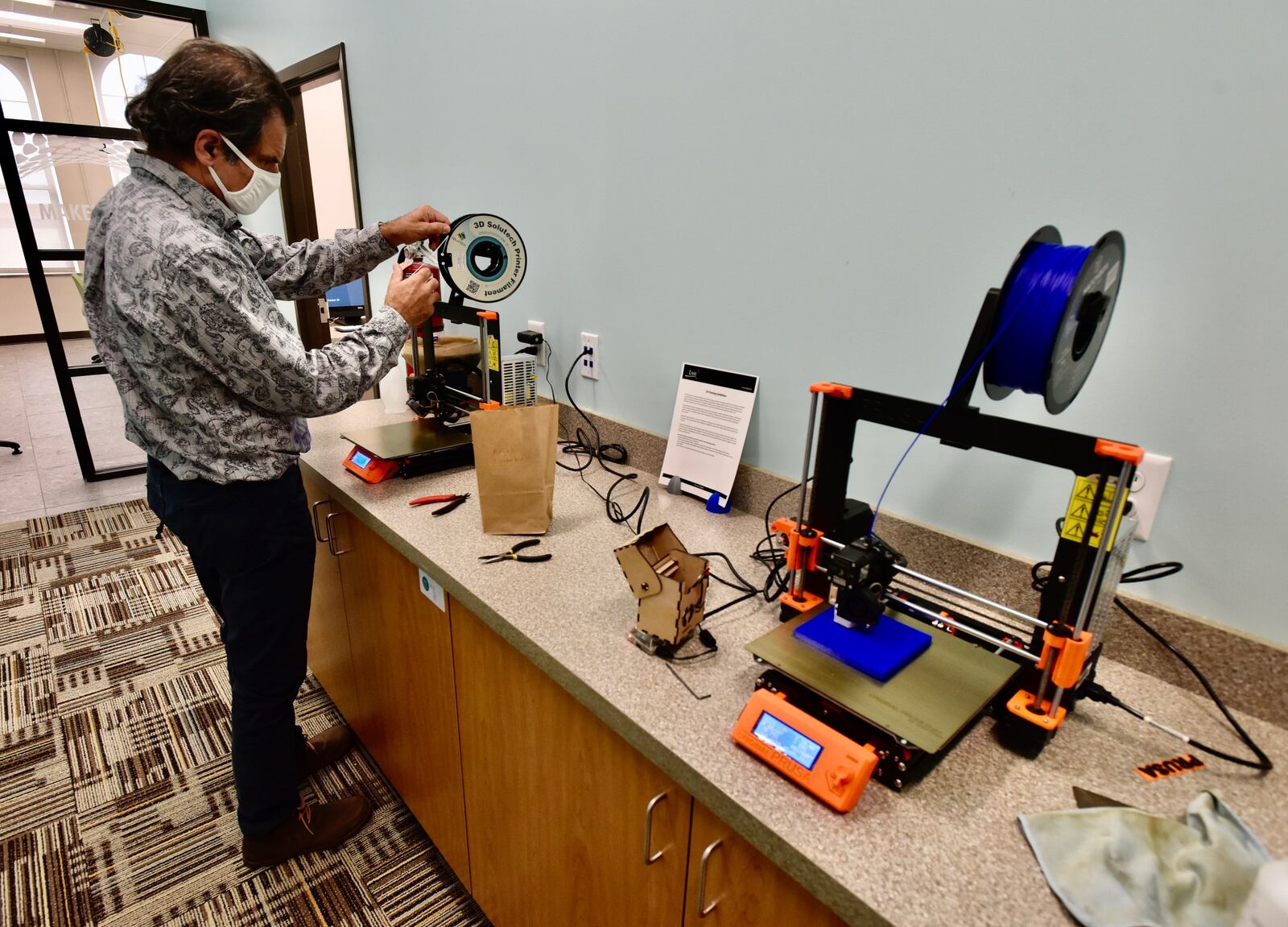 Matt Benzing feeds material to start a project on a 3D printer Tuesday at the Lane Library Community Technology Center in downtown Hamilton. NICK GRAHAM/STAFF