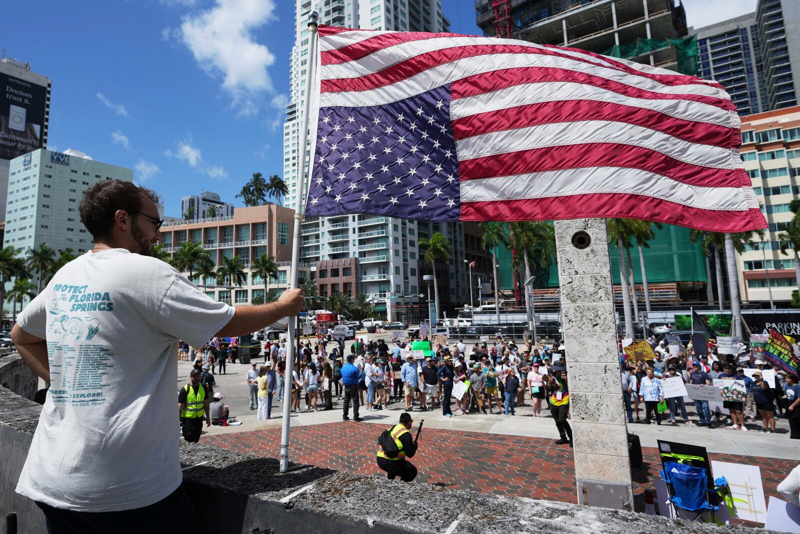 Alberto Rosales holds a U.S. flag upside down for what he calls a "symbol of crisis" during a protest against the Trump administration, Saturday, April 19, 2025, in Miami. (AP Photo/Lynne Sladky)