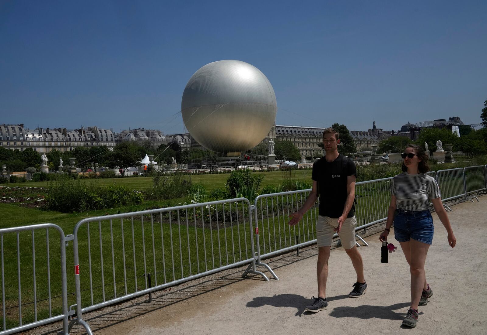 People walk past the Olympic cauldron at the Tuileries Gardens, ahead of its nightly summer relaunch starting June 21, in Paris, Thursday, June 12, 2025. (AP Photo/Michel Euler)