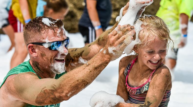 Nate Zettler and Tatum Zettler, 4, put suds on each other during the first day of the MetroParks of Butler County 12th Annual Mud Mania event Friday, Aug. 10 at Rentschler Forest MetroPark on Reigart Road in Fairfield Township. The event features mud volleyball tournaments, giant water slide, slimy obstacle course, muddy pools, vendors, and more. NICK GRAHAM/STAFF