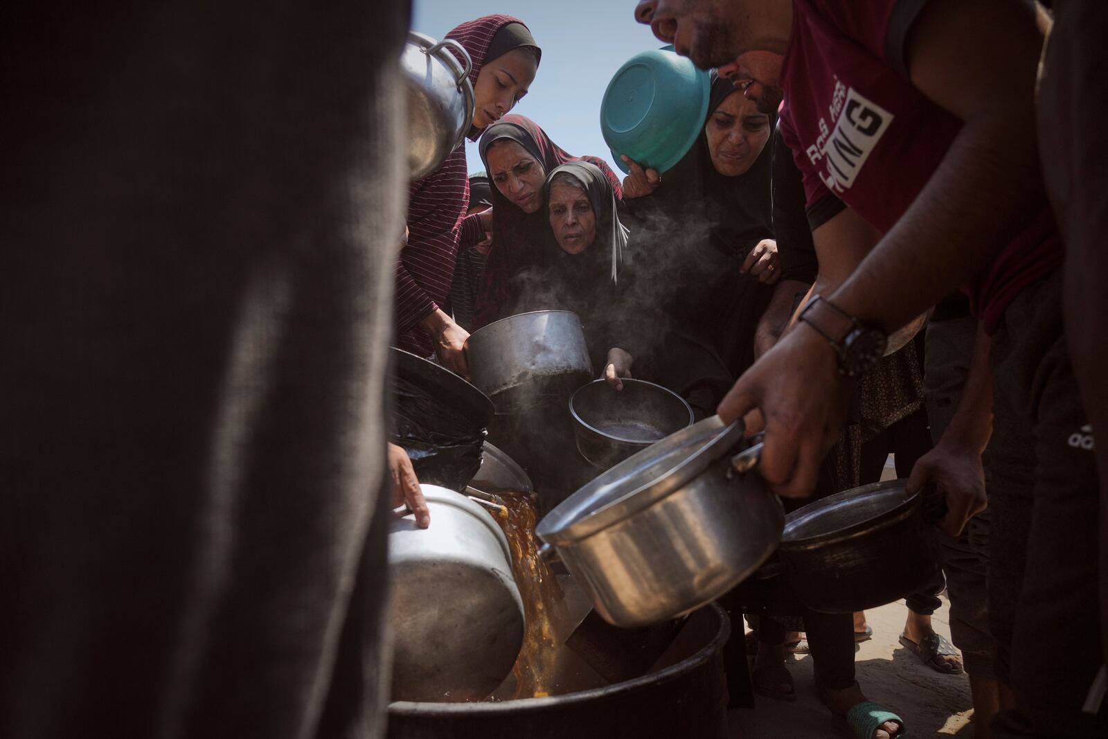 Displaced Palestinians receive donated food at a community kitchen in Gaza City, northern Gaza Strip, Tuesday, July 22, 2025. (AP Photo/Jehad Alshrafi)