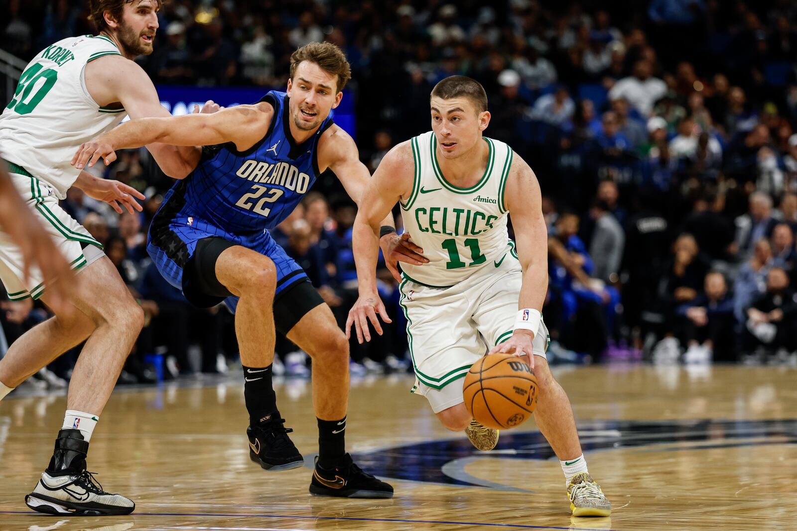 Orlando Magic forward Franz Wagner (22) fights through the screen by Boston Celtics center Luke Kornet, left, as he guards Boston Celtics guard Payton Pritchard (11) during the first half of an NBA basketball game, Wednesday, April 9, 2025, in Orlando, Fla. (AP Photo/Kevin Kolczynski)