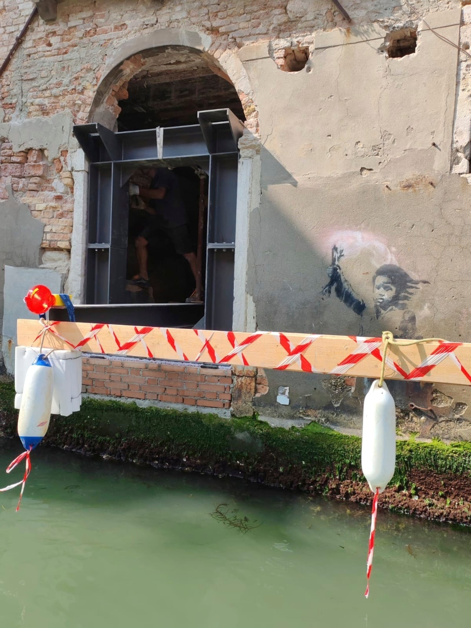In this picture made available Thursday July 24, 2025, Banksy's work The Migrant Child is removed from the facade of Palazzo San Pantalon in Venice, Italy, to complete its rescue. (Ifis Art Via AP)