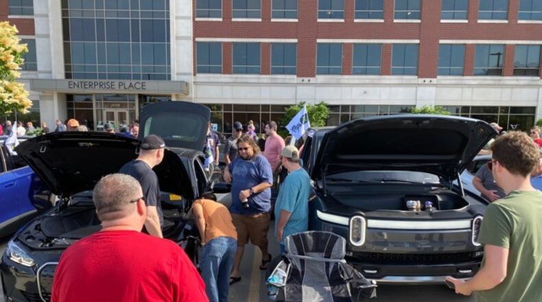 Electric car enthusiasts gather at Dayton Cars & Coffee at Austin Landing Saturday, June 4. Attendees inspect a BMW i4 on the left, and a Rivian R1T on the right. CONTRIBUTED