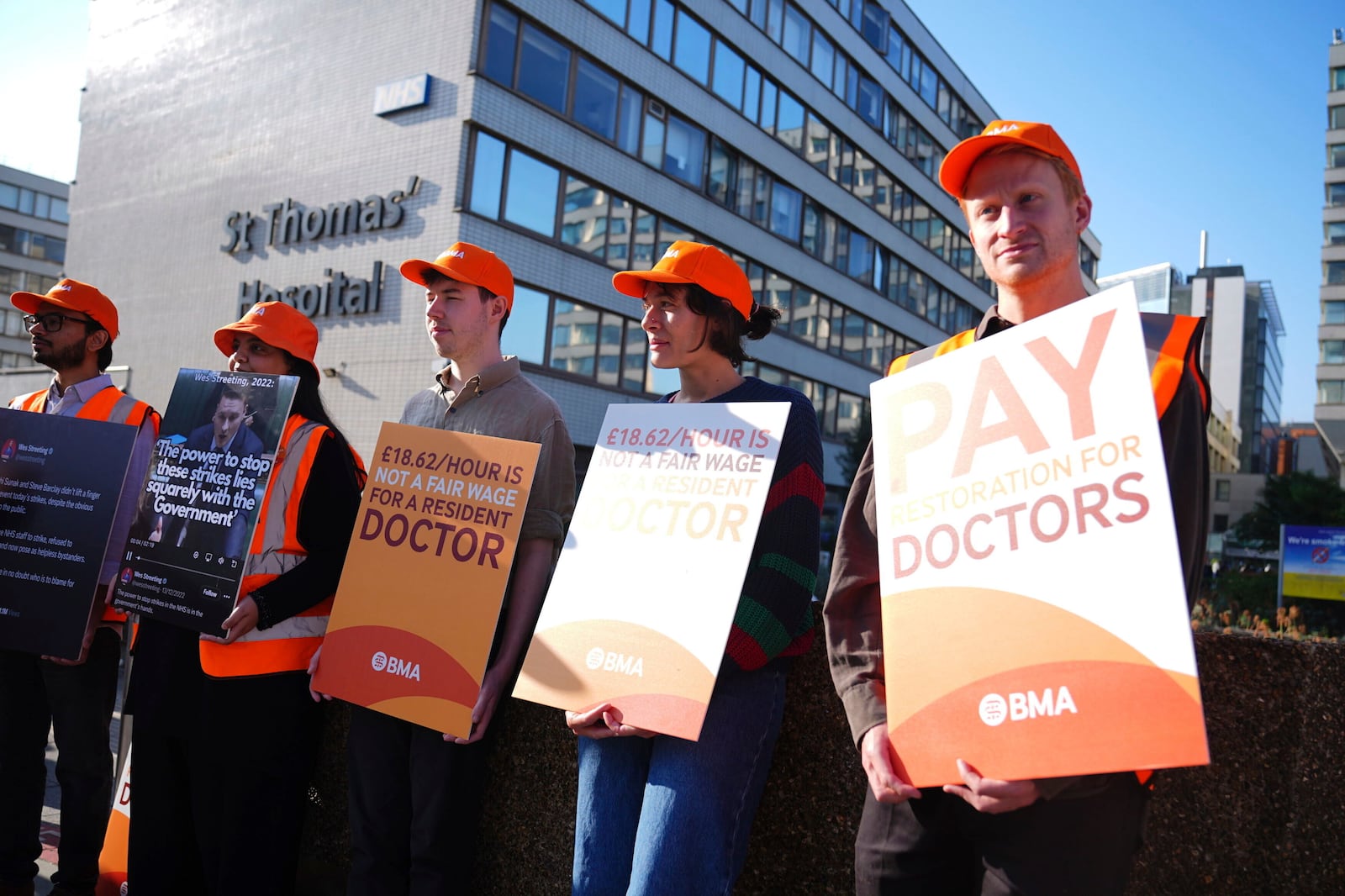 NHS resident doctors hold placards outside St Thomas' Hospital in London, as resident doctors in England, formerly referred to as junior doctors, begin a five-day strike after talks with the government collapsed over pay, Friday, July 25, 2025. ( James Manning/PA via AP)