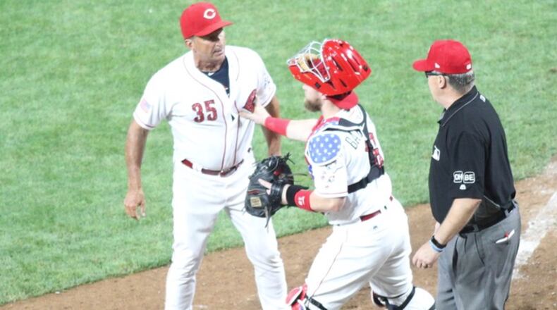 Reds catcher Tucker Barnhart holds back interim manager Jim Riggleman as he argues with Eric Cooper in the 12th inning of a game against the Chicago White Sox on Tuesday, July 3, 2018, at Great American Ball Park in Cincinnati. David Jablonski/Staff