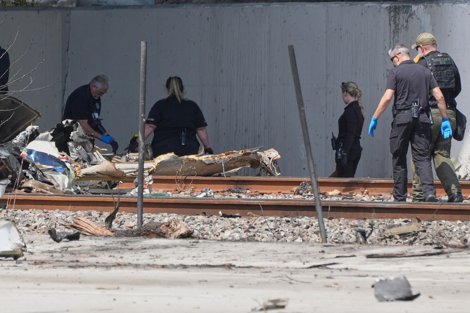 Emergency personnel respond to the area where a small plane crashed on the railroad tracks beneath the overpass near Interstate 95 in Boca Raton, Fla., on Friday, April 11, 2025. (AP Photo/Marta Lavandier)