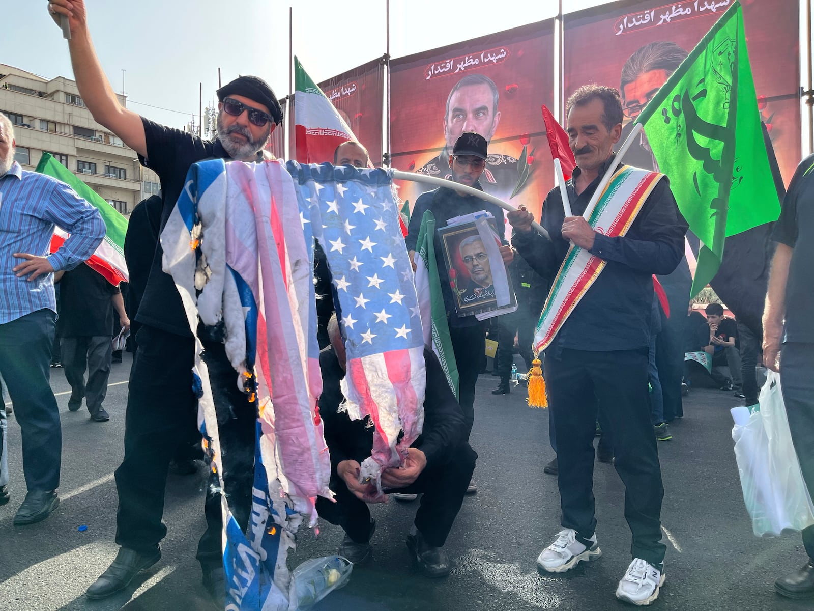 People burn a U.S. flag as they take part in a funeral ceremony of Iranian army generals, nuclear scientists and their family members who were killed in Israeli strikes, in Tehran, Iran, Saturday, June 28, 2025. (AP Photo/Vahid Salemi)