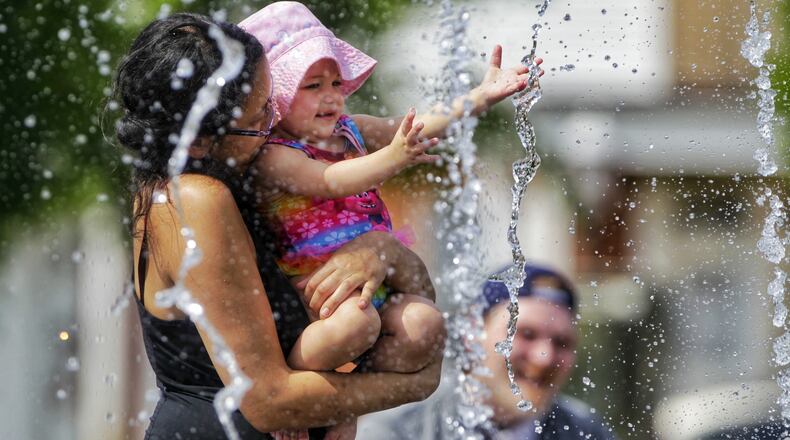 Sydney Engelhard and Kiara Bean, 1, play in the water at the splash pad at Marcum Park Thursday, May 20, 2021 in Hamilton. NICK GRAHAM/STAFF