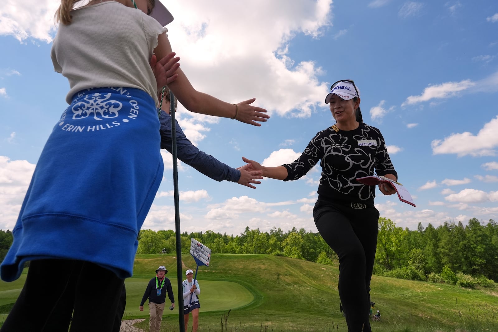 A Lim Kim, of South Korea, greets fans walking to the third tee during the first round of the U.S. Women's Open golf tournament at Erin Hills Thursday, May 29, 2025, in Erin, Wis. (AP Photo/Jeff Roberson)