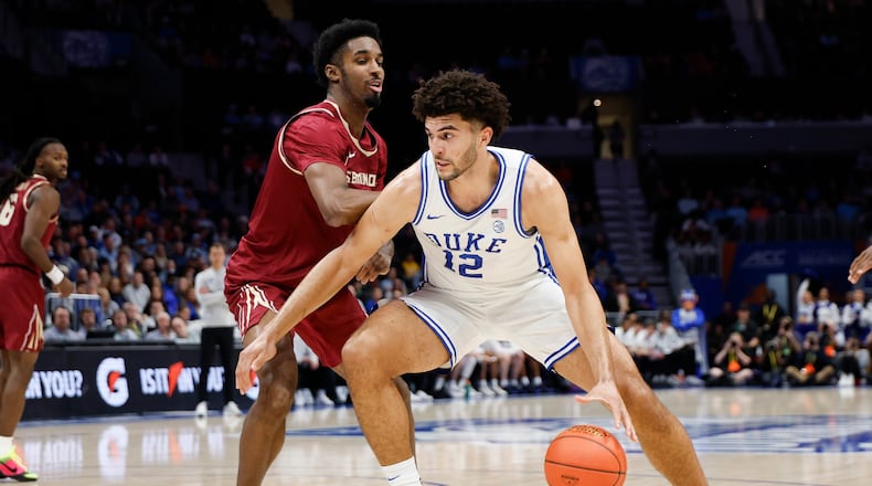 Duke forward Cameron Boozer (12) drives against Florida State forward Chauncey Wiggins during the first half of an NCAA college basketball game in the quarterfinals of the Atlantic Coast Conference tournament in Charlotte, N.C., Thursday, March 12, 2026. (AP Photo/Nell Redmond)