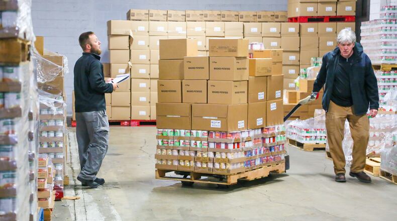 Shared Harvest Food Bank employees Nate Hoskins and Rick Devine pull pantry orders from the warehouse. The Lane Libraries in Butler County will take $1 off library fines for every non-perishable food item a person donates through Dec. 31. GREG LYNCH/STAFF