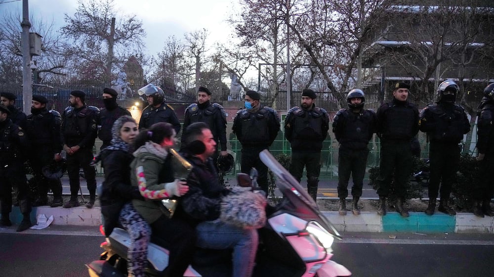 Policemen protect the British Embassy during a protest by hardline supporters of the Iranian government, as people ride on their motorbike in Tehran, Iran, Wednesday, Jan. 14, 2026. (AP Photo/Vahid Salemi)