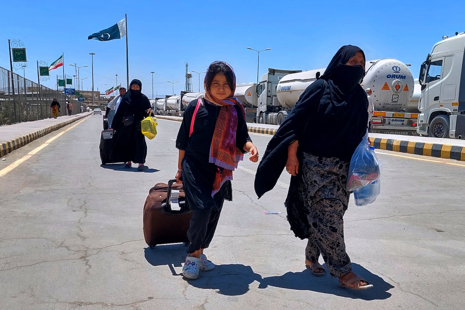 Pakistani families, who were stuck in Iran due to Israeli strikes on Iran, walk toward immigration counter after entering in homeland through Taftan, a joint border crossing point on Pakistan Iran border, Wednesday, June 18, 2025. (AP Photo/Fateh Muhammad)