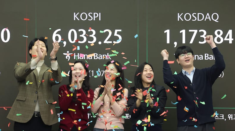 Currency traders celebrate as they work in the office with a screen showing the Korea Composite Stock Price Index (KOSPI) of over 6,000 points at a dealing room of Hana Bank in Seoul, South Korea, Wednesday, Feb. 25, 2026. (Kim Sung-min/Yonhap via AP)