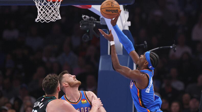 Oklahoma City Thunder guard Shai Gilgeous-Alexander, right, shoots next to Portland Trail Blazers center Donovan Clingan, left, and Thunder center Isaiah Hartenstein during the first half of an NBA basketball game, Sunday, Nov. 23, 2025, in Oklahoma City. (AP Photo/Nate Billings)
