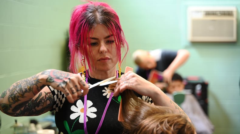 Biz Jarvis, owner of Hue Mane Salon in Hamilton, is giving back to the community when she offered free haircuts to the kids that attend the Boys and Girls Clubs of Hamilton on Grand Boulevard. She's pictured here giving a haircut to a girl at the Boys and Girls Club on Wednesday, July 31, 2024. MICHAEL D. PITMAN/STAFF